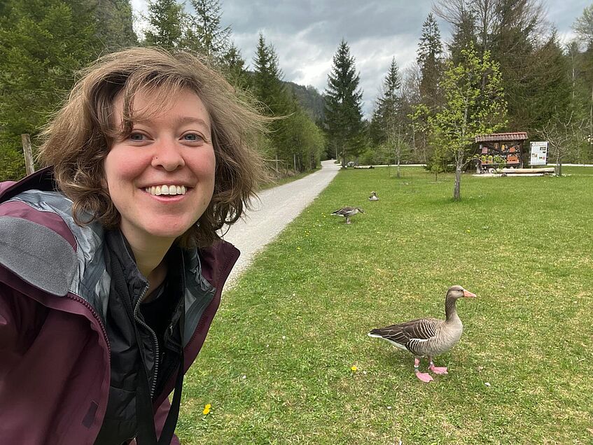 young woman with greylag geese in the background