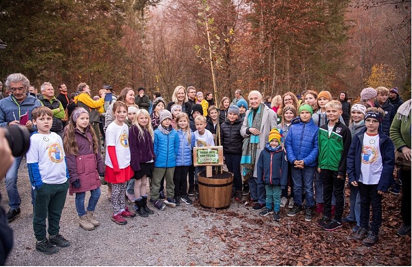 a group of school children with Jane Goodall and a tree