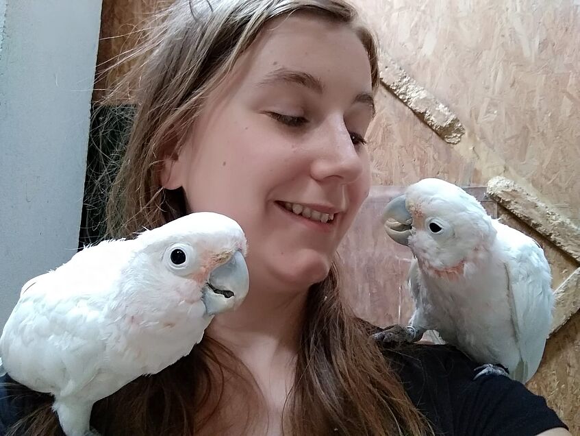 young female scientist with 2 cockatoos on her shoulders