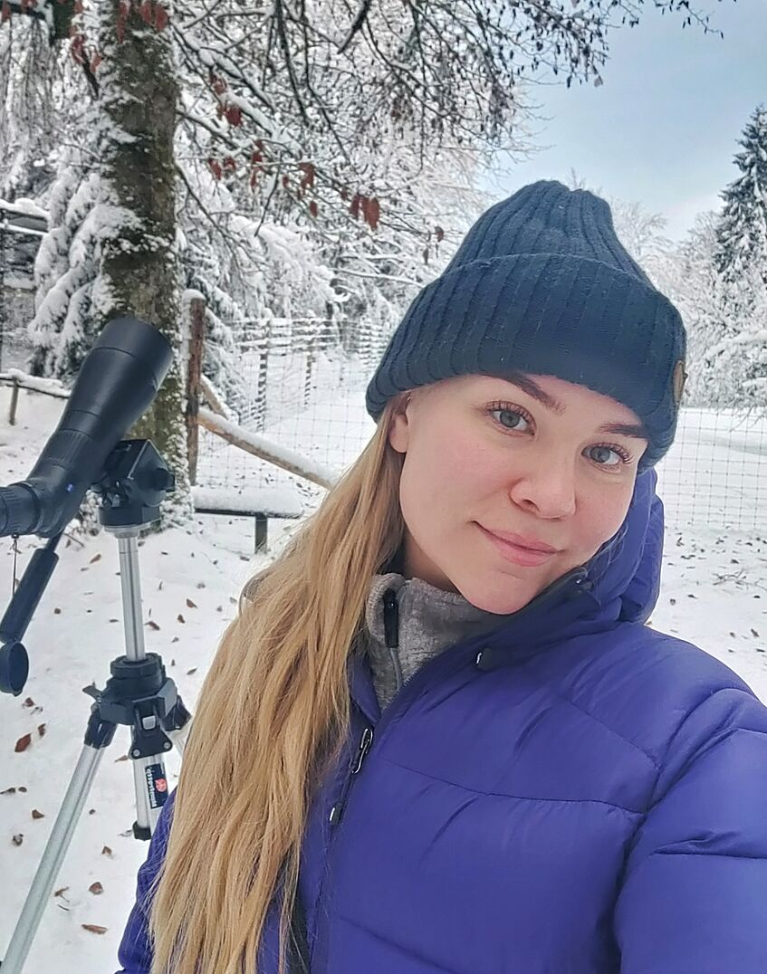 Portrait of a woman in winter, scope on tripod in the background