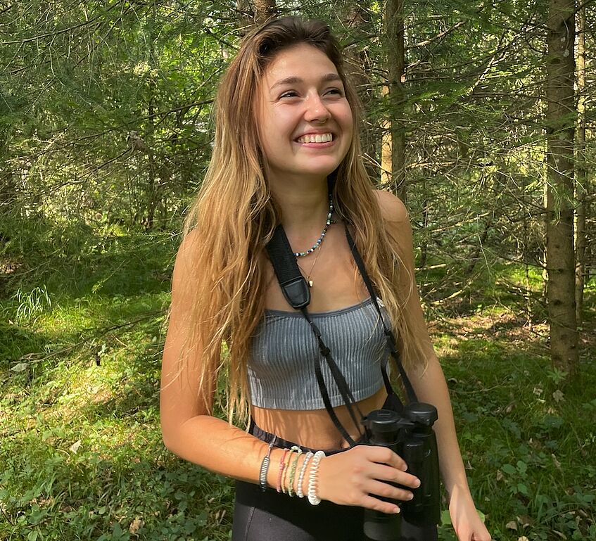 young woman with binoculars in the forest