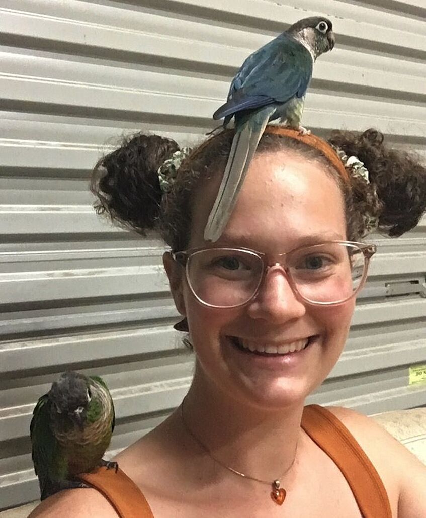 girl with one bird sitting on top of her head and one on her shoulder