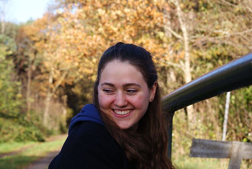 portrait of a woman, in the background a forest in autumn colours