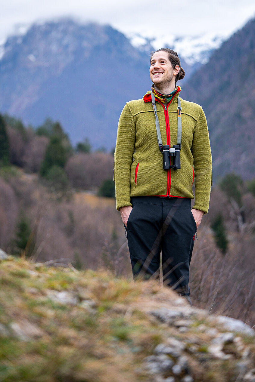 Young man with binoculars inthe mountains