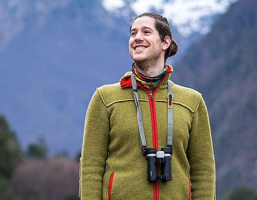 portrait of a young man in the mountains, with binoculars