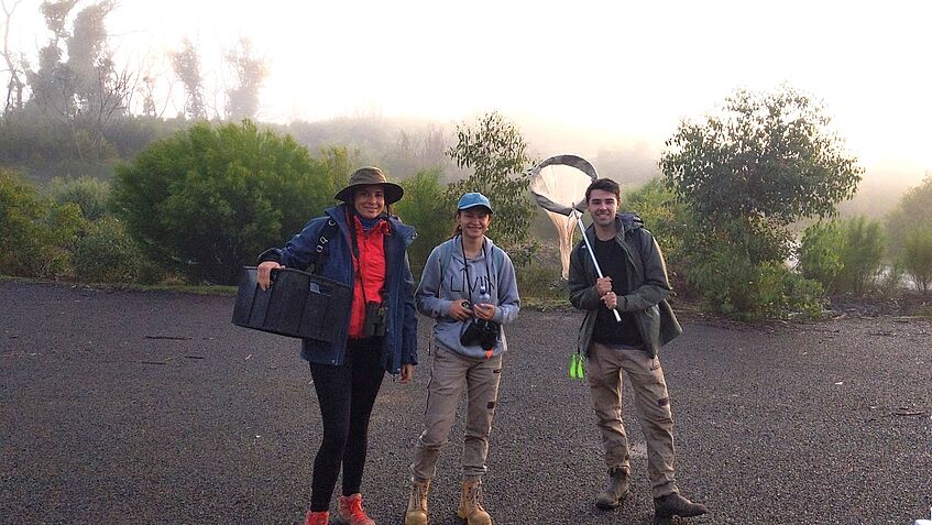 Three researchers with equipment in the field