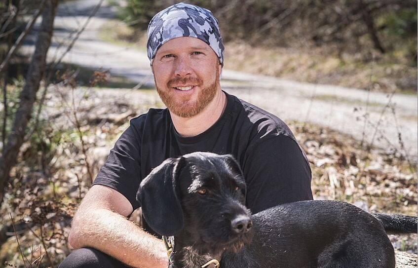 Man kneeling with black dog on a leash