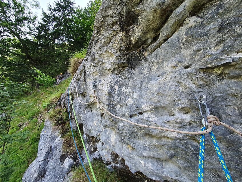 climbing route on the rock, man with helmet waiting at the end